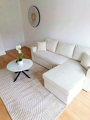 A living room with a white sofa, a round coffee table, and a patterned rug.