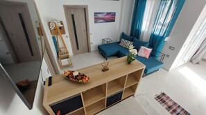 Ein modernes Wohnzimmer mit einem blauen Sofa, einem Holztisch mit Dekoration, einer Strickleiter und einem Bild an der Wand.