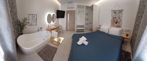 Et moderne hotelværelse med en stor seng, et badekar, et garderobeskab og et fladskærms-tv.