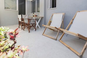 Et udendørs siddeområde med et bord, stole og staffelier.