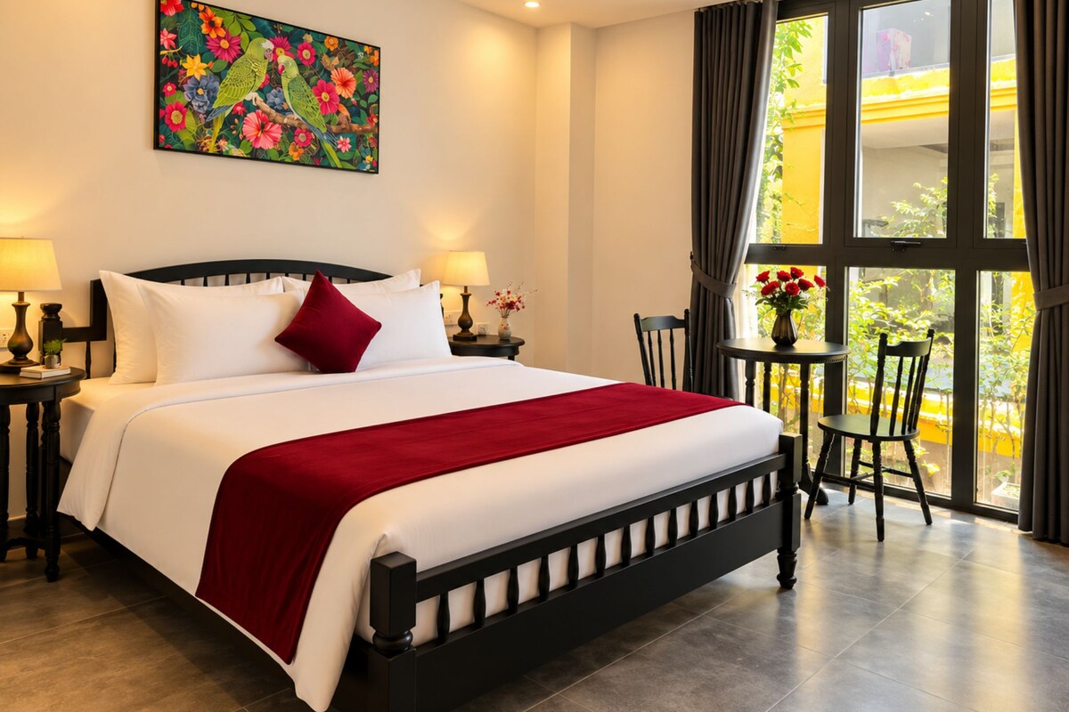 Quarto de hotel com uma cama, duas mesas de cabeceira, uma janela com cortinas, uma cadeira e um quadro na parede.