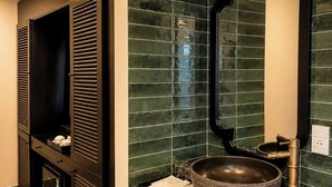 Un baño moderno con un espejo grande, un lavabo de pedestal redondo y una cabina de ducha integrada.