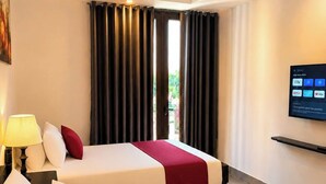 Habitación de hotel con dos camas, un televisor y una ventana con cortinas.