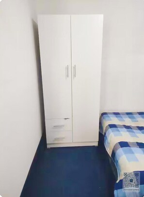 A room with a white wardrobe, a bed with a checkered bedspread, and a blue carpet. - Safe and Peaceful Studio in vibrant central Cape Town neighborhood (Cape Town)