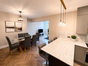 Una cocina moderna con encimera de mármol, suelo de parqué tipo espiga y luminarias colgantes.