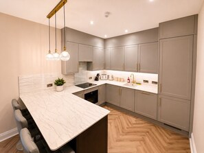 Una cocina moderna con encimeras de mármol, armarios grises y un suelo de madera en patrón de espiga.