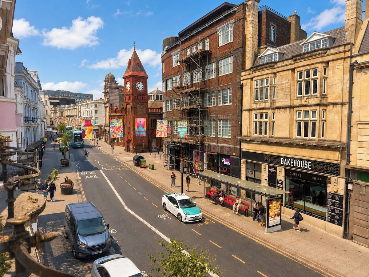 A street view with a clock tower, a Bakehouse shop, and a bus lane.