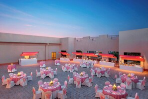 An outdoor event space with multiple round tables, each with white chairs and pink tablecloths. - Itc Rajputana A Luxury Collection Hotel (Jaipur)