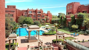 Un cortile alberato di un hotel con piscina, sdraio e giardino.