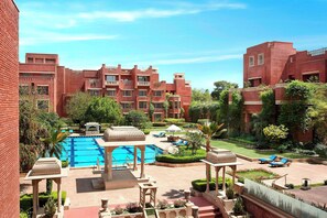 Une cour d’hôtel avec une piscine, des chaises longues et un jardin.