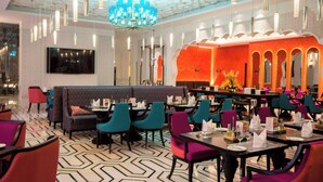 Un ristorante dall'arredamento moderno, con pavimento decorato, diverse opzioni di posti a sedere tra cui cabine e tavoli, e un lampadario centrale.