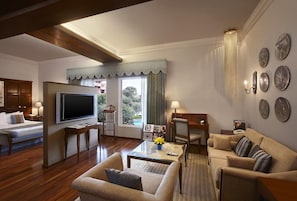 A well-appointed hotel room with a large bed, a television, a seating area with a sofa and armchairs, a coffee table, and a view of the outdoors. - Itc Rajputana A Luxury Collection Hotel (Jaipur)
