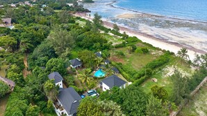 A coastal property with a swimming pool, houses, and a beach.
