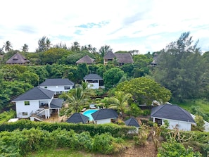 A residential area with houses, a swimming pool, and lush greenery. - Coast Sun Gardens Cottage Adults Only (Msambweni)