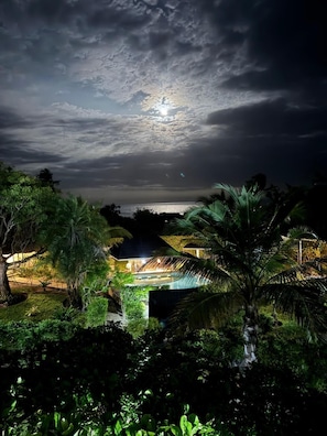 A nighttime view of a resort with a pool, surrounded by lush greenery and palm trees, under a cloudy sky. - Coast Sun Gardens Cottage Adults Only (Msambweni)