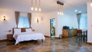A bedroom with a stone floor, a bed, a desk, and a chair.