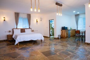 A bedroom with a stone floor, a bed, a desk, and a chair. - Coast Sun Gardens Cottage Adults Only (Msambweni)