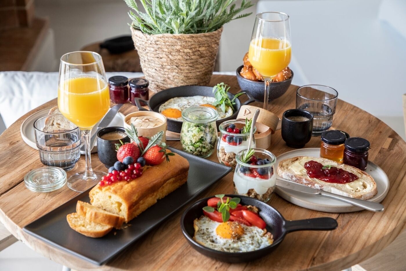 A breakfast setting with various food items, drinks, and condiments on a wooden table.