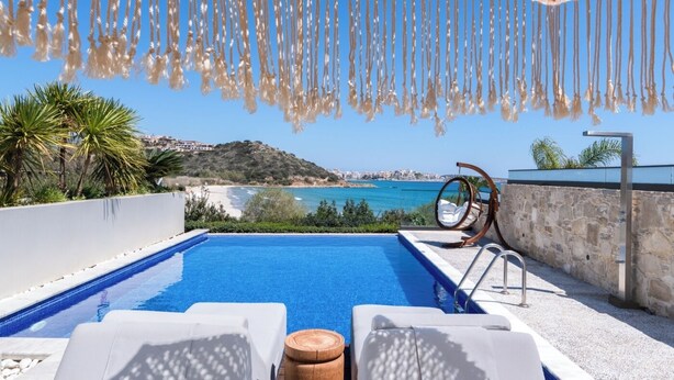 A rooftop pool with a view of the sea, lounge chairs, and a hanging chair. - The Sand Suites (Agios Nikolaos)