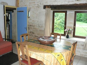 A dining area with a table set for four, a blue door, and a view of greenery outside.