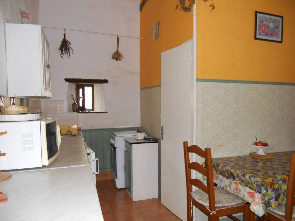A compact kitchen with a dining area, a microwave, a refrigerator, and a small table with a floral tablecloth.