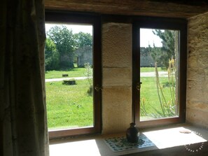 A room with a large window, a stone wall, and a small vase on the windowsill.
