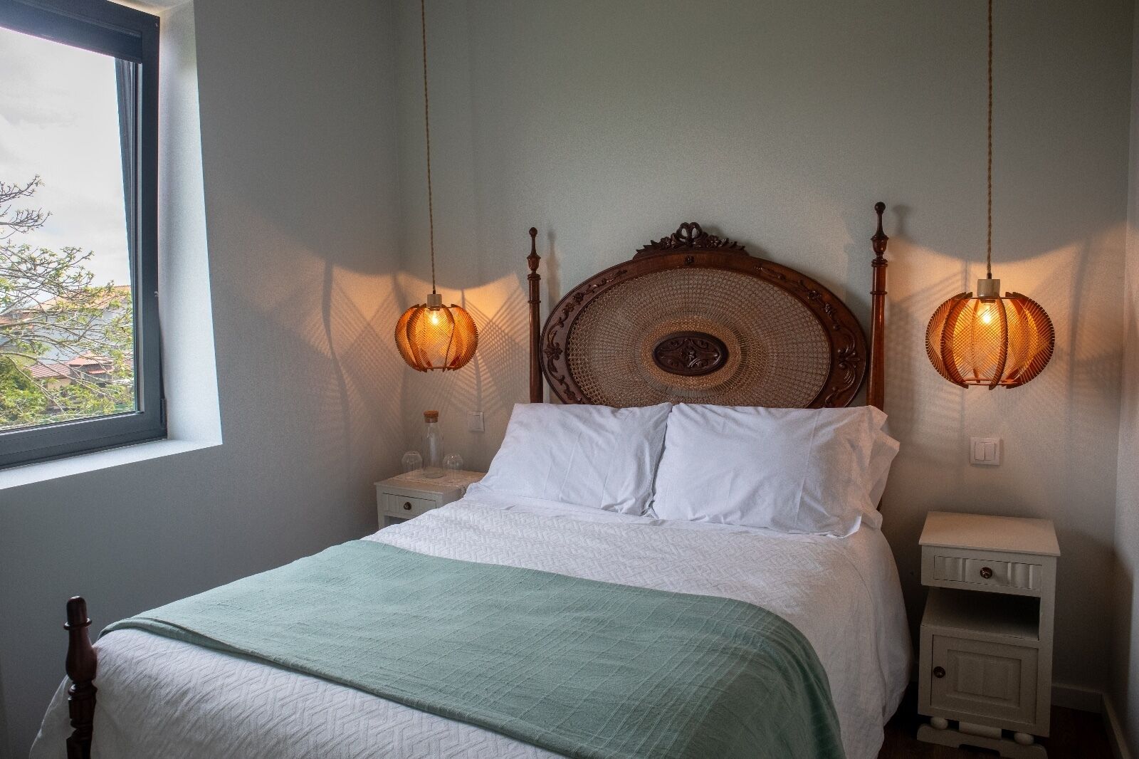 Ein Schlafzimmer mit einem Bett, zwei Nachttischen, einem Fenster und zwei Wandlampen.