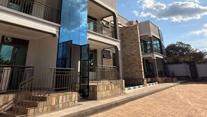 A multi-story building with a modern architectural design, featuring a mix of glass and stone facades, and a paved courtyard. - Elite Apartments (Kigali)