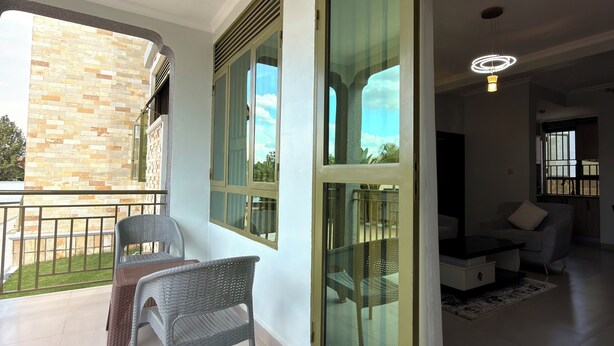 A spacious living area with a balcony, large windows, and a modern light fixture. - Elite Apartments (Kigali)