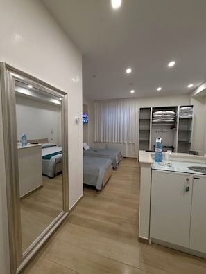 Une chambre dâhĂŽtel avec un grand miroir, deux lits, une petite kitchenette et un tĂ©lĂ©viseur.