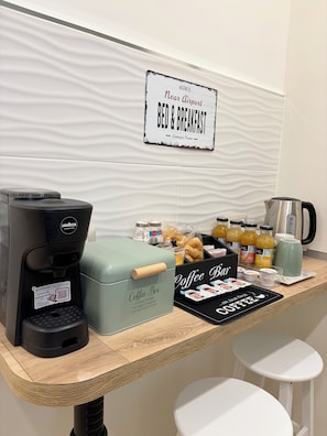 Una zona de cafetería con una máquina de café, un dispensador de café y un letrero que indica servicio de casa de huéspedes.