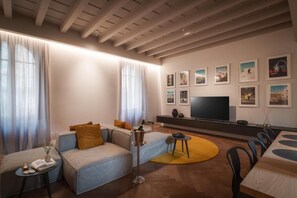 Ett modernt vardagsrum med en soffa, ett soffbord, en tv och inramade tavlor på väggen.