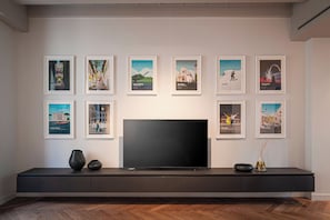 A modern living room with a large flat-screen TV, a dark console table, and framed artwork on the wall. - Residenza Palazzo Farinati (Verona)