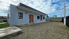 A modern single-story building with a flat roof, a front door, and a small porch area. - 3 bedroom villa,5 minutes to the main beach driving 3 minute to other beach (Cabarete)