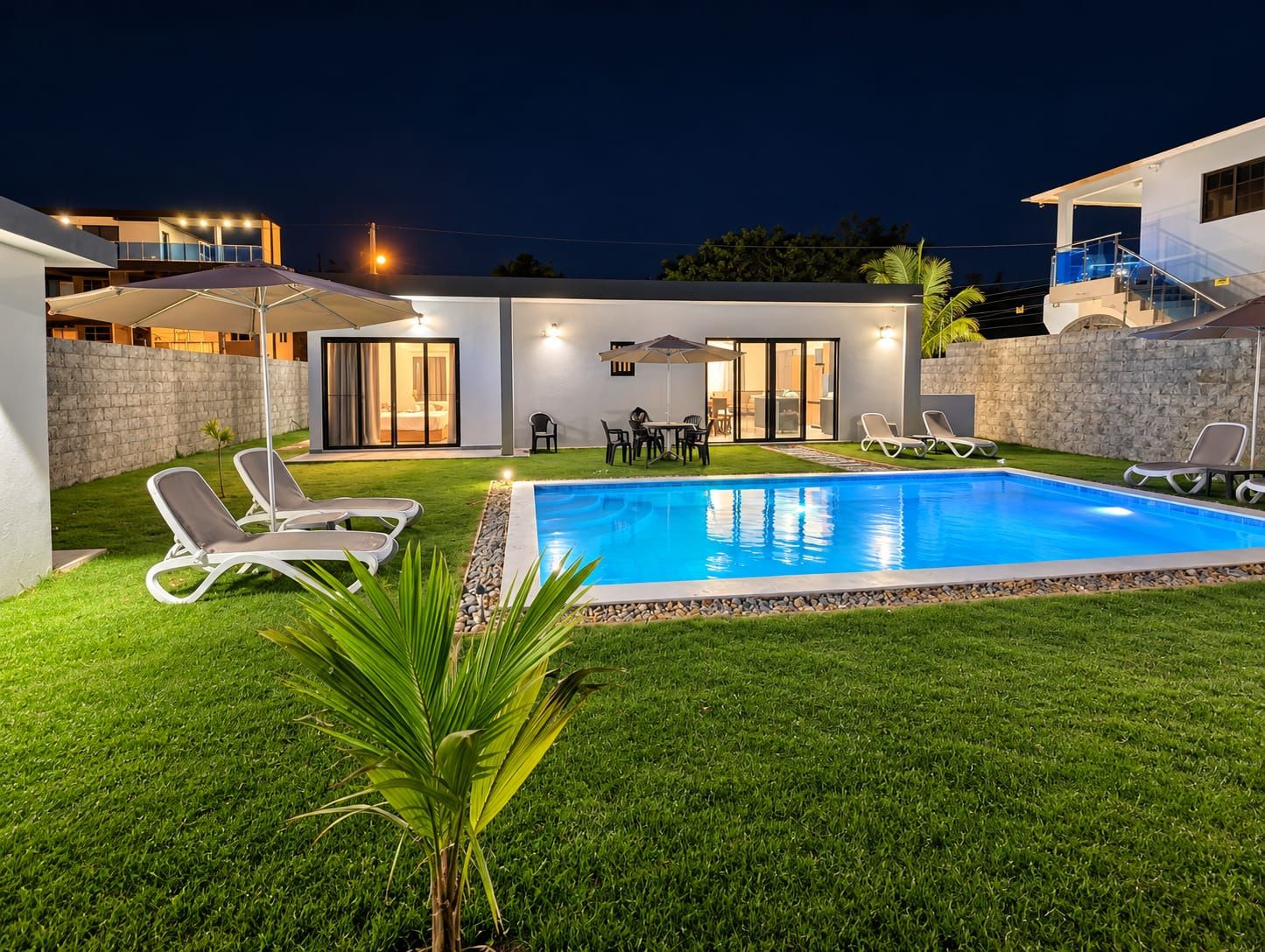A modern outdoor pool area with lounge chairs and a dining set.