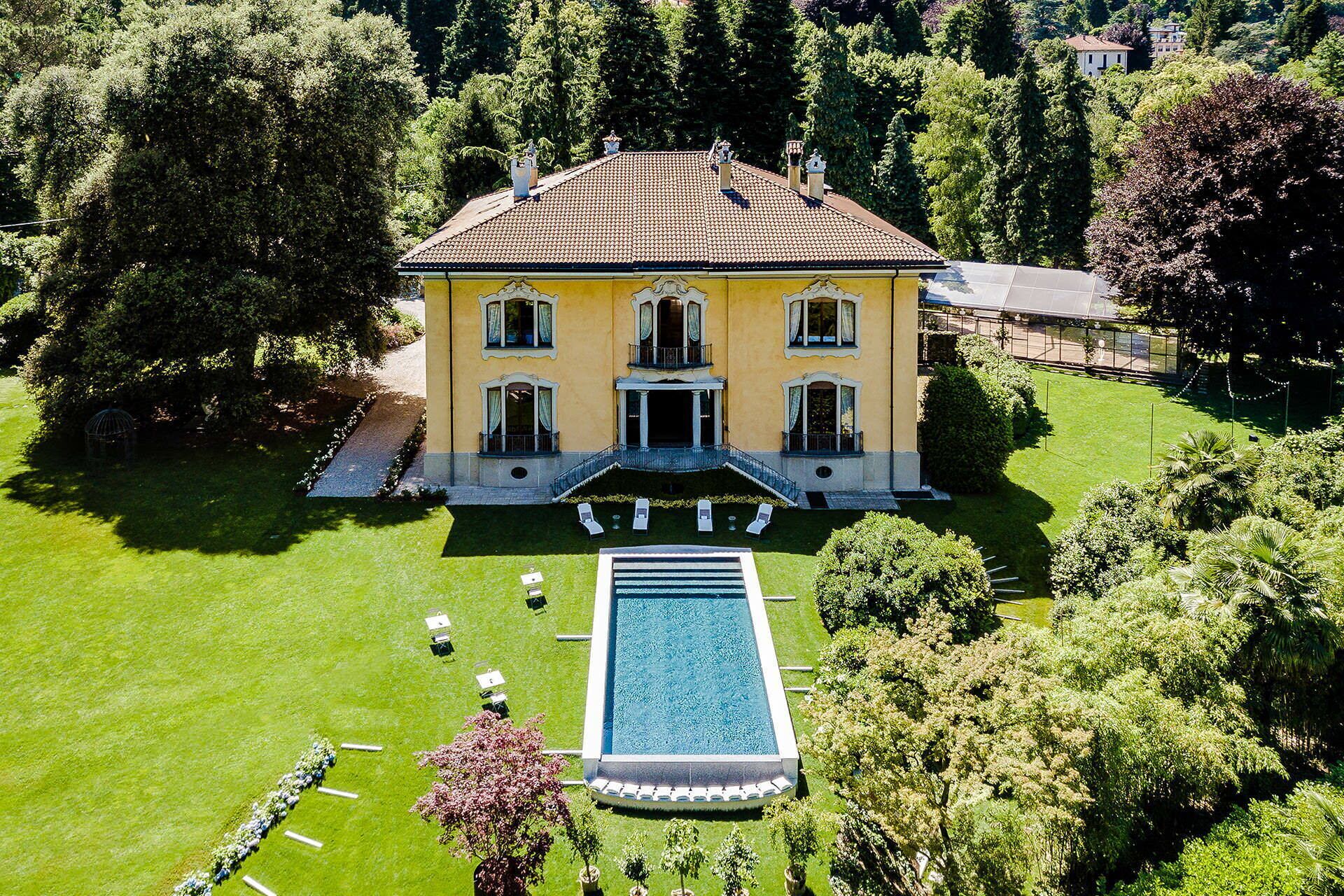 A large yellow building with a swimming pool and a well-maintained lawn.