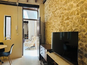 Ein Zimmer mit Stehwänden, einem Fernseher, einem Schreibtisch, einem Stuhl und einer Tür zu einem anderen Raum.