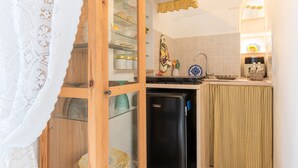 A compact kitchen with a refrigerator, a sink, and a glass cabinet with dishes. - Fioredoro Holiday Home with Air Conditioning (Martina Franca)