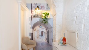 A narrow hallway with a chair, a table with a bottle, and hanging plants. - Fioredoro Holiday Home with Air Conditioning (Martina Franca)