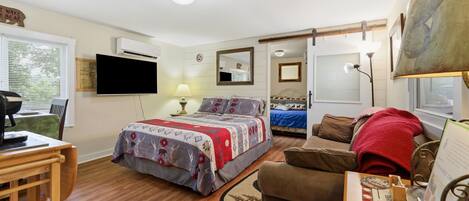 Een slaapkamer met een bed, een bureau, een stoel, een televisie en een raam.