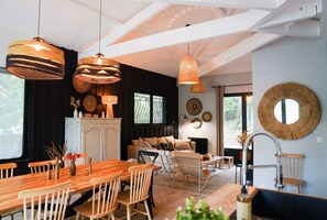 Een moderne woonkamer met een houten eettafel, twee banken en een keuken met een witte kast.