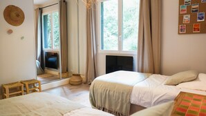 A bedroom with two beds, a mirror, a fireplace, and a window with curtains. - La Petite Pinède : a peaceful villa between pines and a pond - La Pointe aux Chevaux (Lège-Cap-Ferret)
