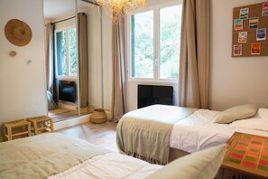 Een slaapkamer met twee bedden, een spiegel, een open haard en een raam met gordijnen.