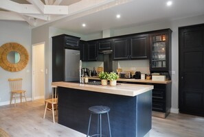 Een moderne keuken met donkere kasten, een centraal eiland en een houten stoel.