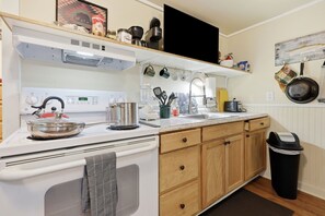 A kitchen with a stove, sink, and wooden cabinets. - Whittier Cabin Retreat for Large Groups (Whittier)