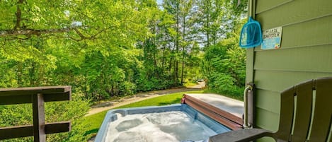 A hot tub on a wooden deck with a sign indicating a shower before the tub.