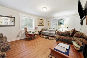 Ein Wohnzimmer mit Esstisch, zwei Sofas, einem Couchtisch und einem Fernseher.