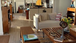 A living room with a sofa, coffee table, and a dining area with a wooden table. - Waterfront 4* villa on the Etel ria. Ideal for families. (Plouhinec)