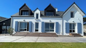 A two-story house with a white exterior, large windows, and a front porch. - Waterfront 4* villa on the Etel ria. Ideal for families. (Plouhinec)