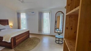 A bedroom with a bed, a ceiling fan, a small table with a plant, and a mirror. - 2-bedroom apartment in lovely Fumba Town with AC, modern comforts and balconies (Nyamanzi)